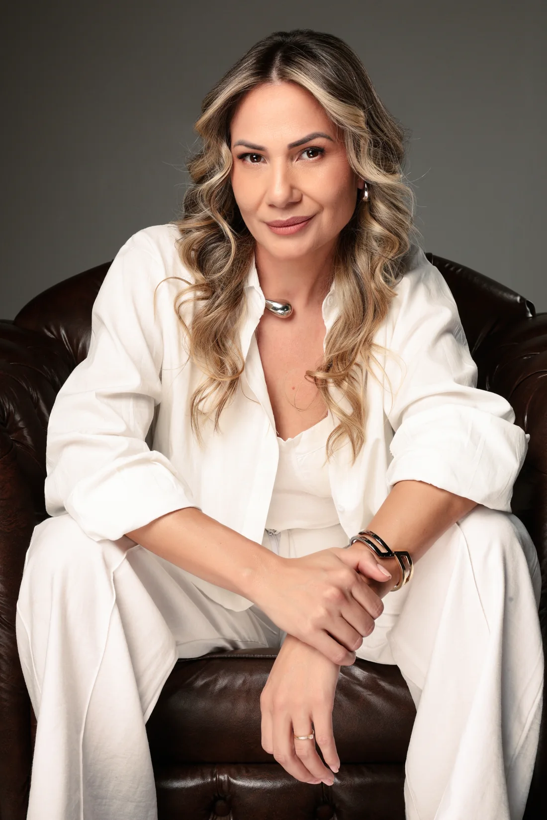 Fabíola Luz sentada em uma poltrona, usando roupa branca